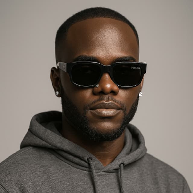 Studio portrait of Godwill Barasa in dark sunglasses and a grey hoodie against a plain grey backdrop