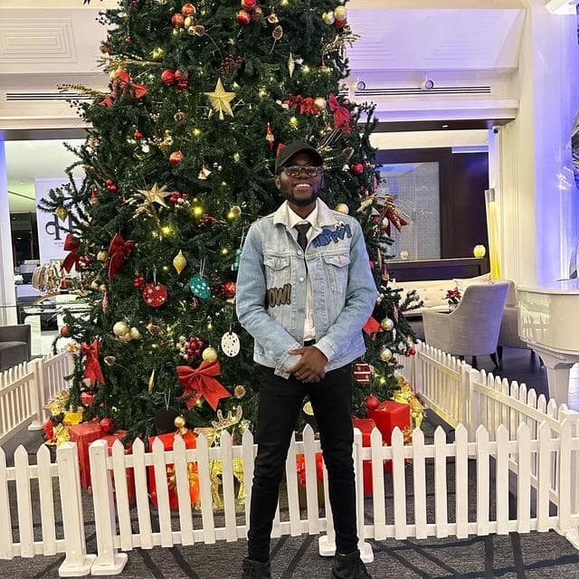 Godwill Barasa standing in a Nairobi hotel lobby beside a decorated Christmas tree